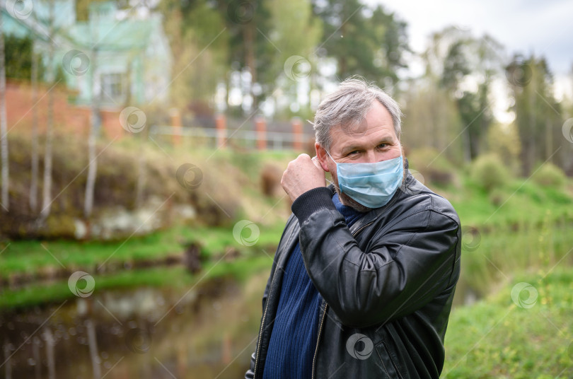 Скачать Счастливый человек на прогулке на природе у реки. Мужчина снимает медицинскую маску со своего лица. фотосток Ozero