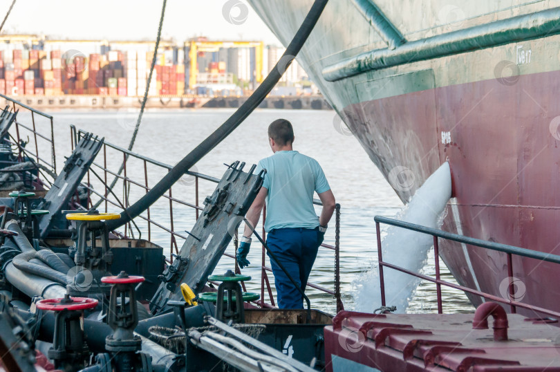 Скачать Россия, Санкт-Петербург, май 2021 года: Сброс балластной воды с палубы нефтяного танкера в бухте порта фотосток Ozero
