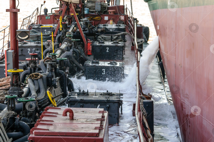 Скачать Россия, Санкт-Петербург, май 2021 года: Сброс балластной воды с палубы нефтяного танкера в бухте порта фотосток Ozero