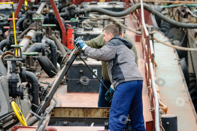 Скачать Россия, Санкт-Петербург, май 2021 года: Два моряка-мужчины работают на палубе нефтяного танкера фотосток Ozero