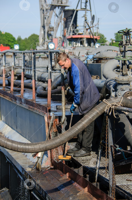 Скачать Россия, Санкт-Петербург, май 2021 года: Рабочий в форме морского пехотинца на палубе нефтяного танкера в бухте в порту фотосток Ozero