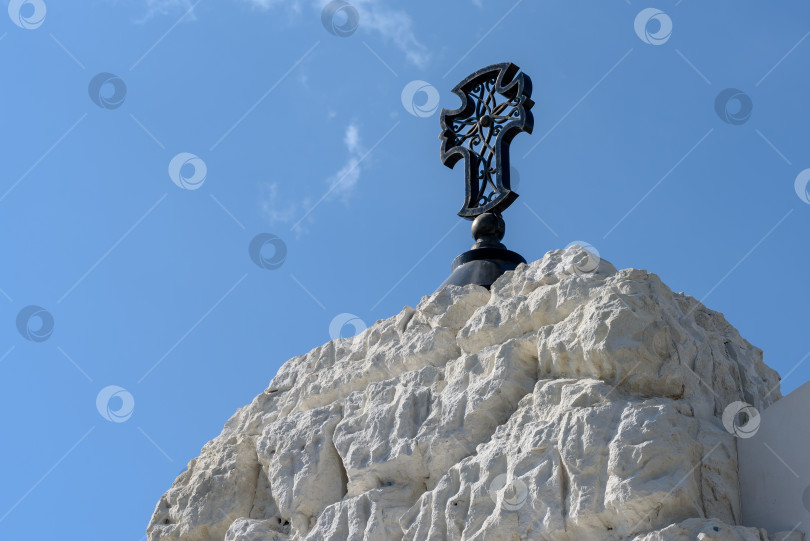 Скачать Железный крест, выкованный на крыше церкви на фоне голубого неба фотосток Ozero