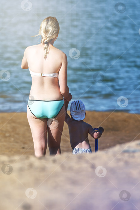 Скачать Молодая женщина с ребенком спускаются к воде на пляже, вид сзади фотосток Ozero
