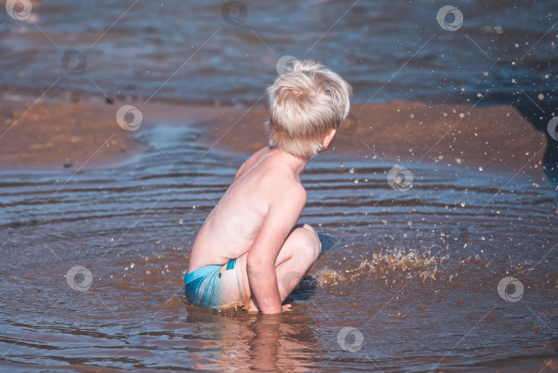 Скачать Маленький ребенок плещется в прибрежной воде фотосток Ozero