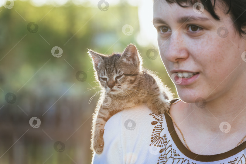 Скачать Маленький котенок сидит на плече у девочки на прогулке. фотосток Ozero