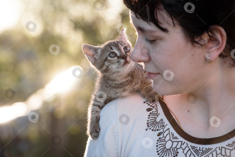 Скачать Маленький котенок сидит на плече у девочки на прогулке. фотосток Ozero