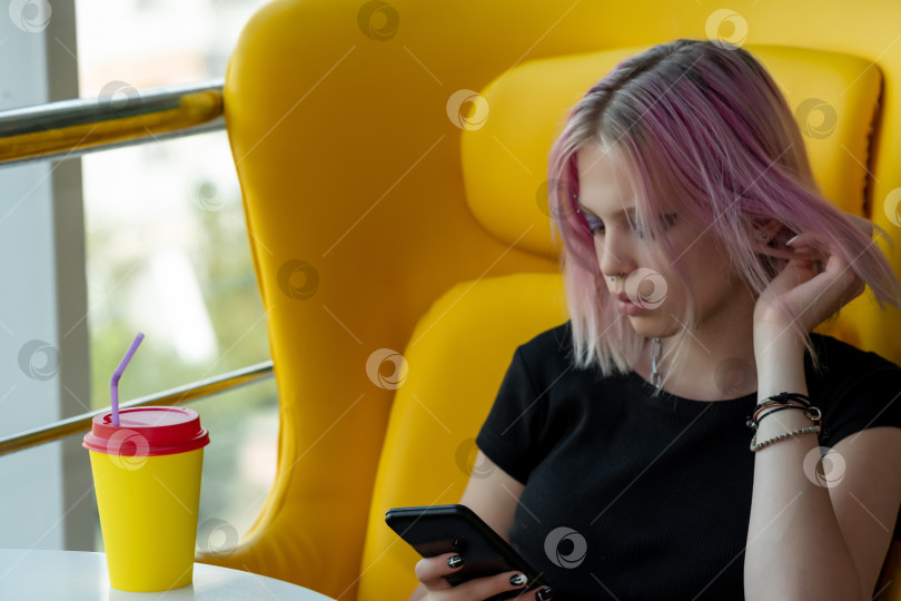 Скачать девочка-подросток пишет или читает сообщение по телефону, сидя в кафе фотосток Ozero