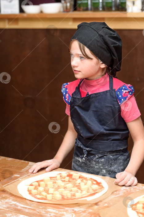 Скачать Маленькая девочка-повар в униформе готовит пиццу на кухне. фотосток Ozero