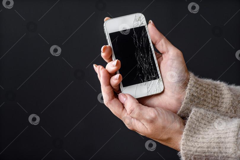 Скачать смартфон с разбитым экраном в женских руках на темном фоне фотосток Ozero