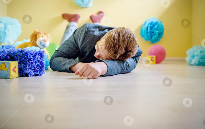 Скачать молодой мужчина-отец заснул на полу в детской комнате среди игрушек фотосток Ozero