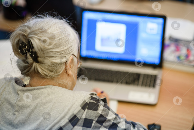 Скачать Пожилая женщина на занятиях в центре досуга изучает работу на компьютере. фотосток Ozero