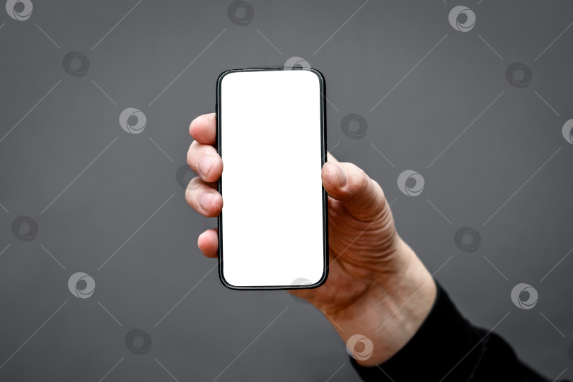 Скачать рамка смартфона с пустым белым экраном на темном фоне в руке мужчины. фотосток Ozero