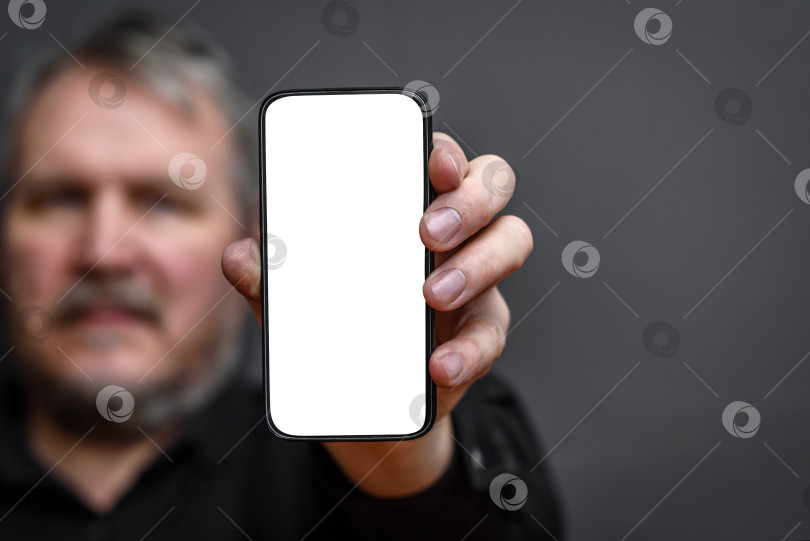 Скачать мужчина держит в руках смартфон с пустым белым экраном фотосток Ozero