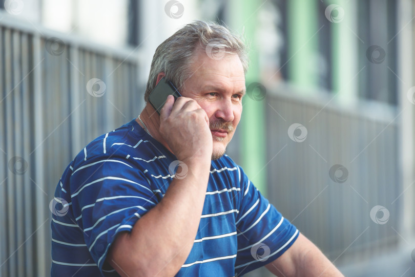 Скачать Мужчина разговаривает по телефону в городе - портрет мужчины, пользующегося устройствами фотосток Ozero
