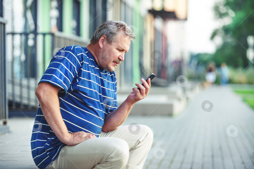Скачать Взрослый красивый мужчина пользуется смартфоном - концепцией коммуникации и технологий. Мужчина разговаривает по телефону в городе фотосток Ozero