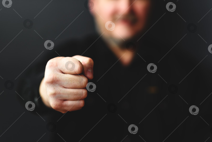 Скачать мужская рука, сжатая в кулак на темном размытом фоне. Понятие гнева, агрессии или решительности фотосток Ozero