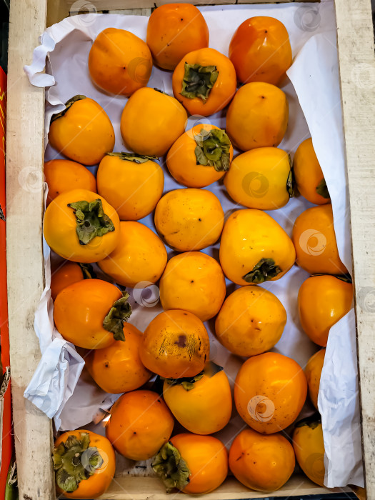 Скачать Свежие плоды хурмы находятся в коробке в магазине фотосток Ozero