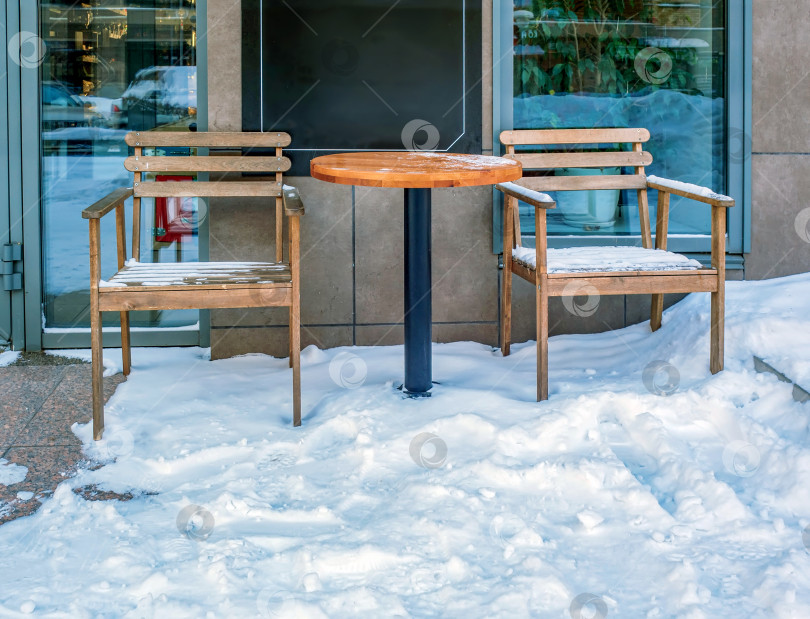 Скачать Стол и стулья уличного кафе зимой покрыты снегом. фотосток Ozero