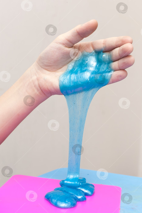 Скачать Современная игрушка под названием slime. Ребенок играет с прозрачной голубой слизью. Руки, держащие слизь, выделенную на белом фоне. Избирательный фокус фотосток Ozero