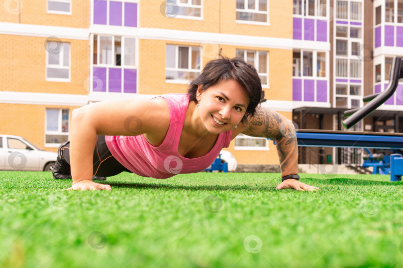 Скачать мускулистая пухленькая женщина делает упражнения для отжимания на спортивной площадке фотосток Ozero