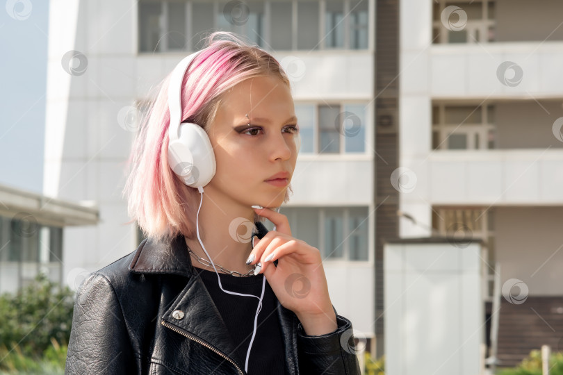 Скачать девочка-подросток слушает музыку в наушниках на открытом воздухе на фоне города фотосток Ozero