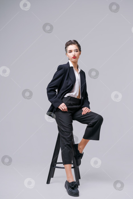 Скачать Красивая молодая бизнесвумен в модном черном костюме и белой рубашке позирует фотосток Ozero