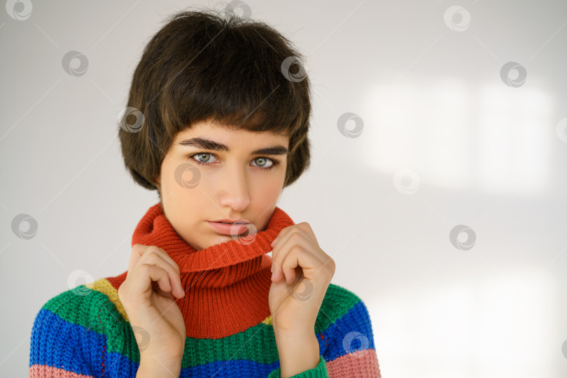Скачать Портрет милой девушки в разноцветном свитере на светлом фоне фотосток Ozero