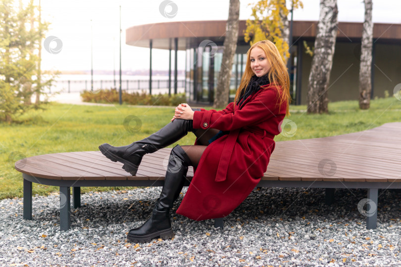 Скачать улыбающаяся девушка, сидящая на скамейке в осеннем парке фотосток Ozero