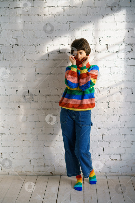 Скачать Портрет молодой женщины в разноцветном свитере, закрывающей лицо свитером. Понятие застенчивости фотосток Ozero