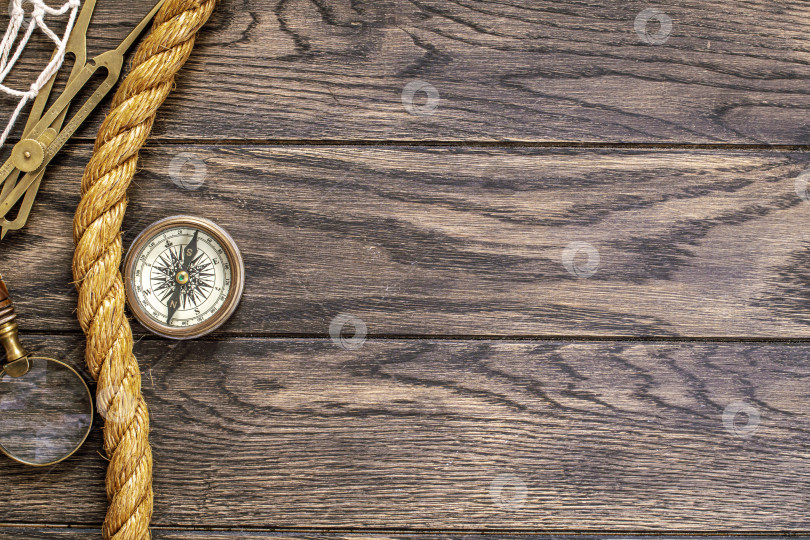 Скачать Старинный компас, увеличительное стекло и тросовая веревка на старом деревянном фотосток Ozero