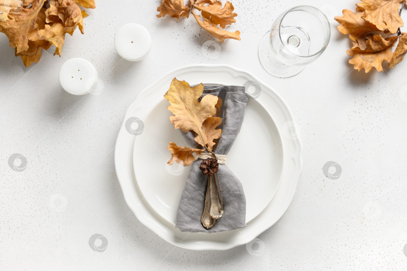 Скачать Осенняя сервировка стола с осенними листьями и белой тарелкой на белом столе. Вид сверху. фотосток Ozero
