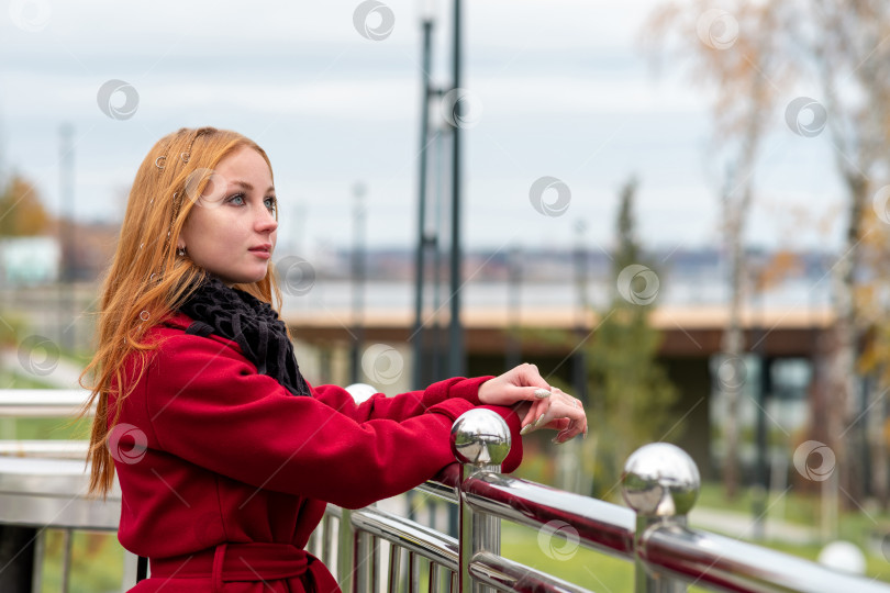 Скачать красивая рыжеволосая девушка смотрит вдаль, стоя над осенней набережной фотосток Ozero