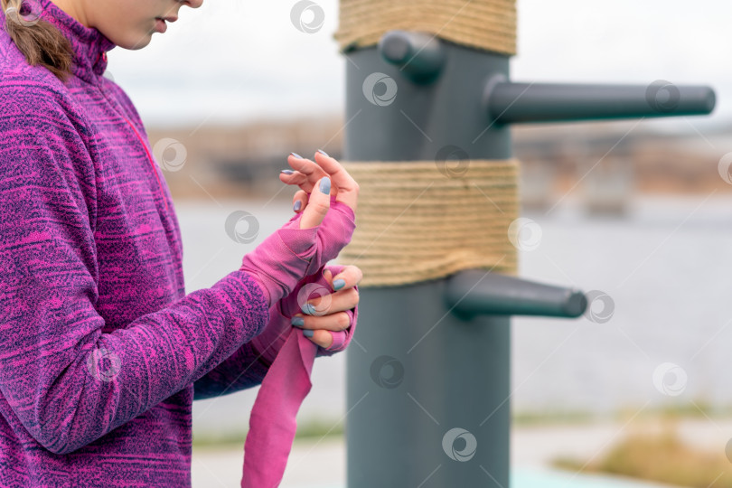 Скачать девушка обматывает запястье вокруг своей руки перед тренировкой по боевым искусствам на открытом воздухе фотосток Ozero