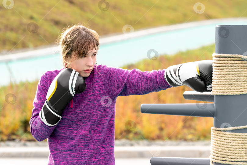 Скачать молодая женщина, практикующая боевые искусства в одиночку на спортивной площадке с традиционными манекенами фотосток Ozero