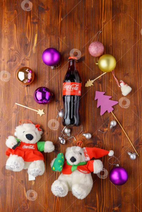 Скачать Тюмень, Россия - 30 августа 2022 года: Coca-Cola Classic в стеклянной бутылке с елочными украшениями, подарками и шарами. Лежал плашмя. Вертикальная фотография фотосток Ozero