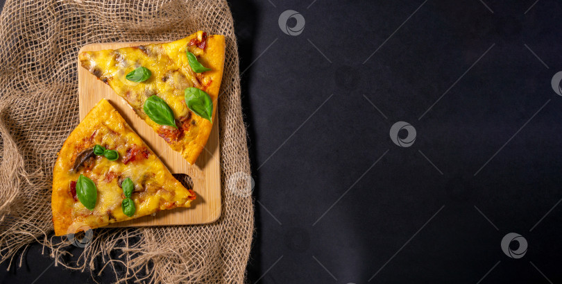 Скачать Кусок запеченной пиццы с грибами и базиликом, помидорами и сыром, черный фон, плоская выкладка, место для копирования фотосток Ozero