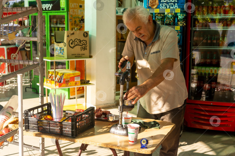 Скачать продавец отжимает гранатовый сок ручным прессом в Кемере, Турция фотосток Ozero