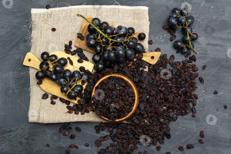 Скачать Сушеный черный изюм в деревянной ложке со свежим спелым виноградом. Полезная закуска, диетический продукт. Плоская поверхность фотосток Ozero