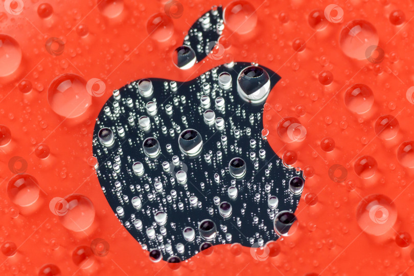 Скачать Тюмень, Россия - 19 июля 2022 года: макрос с красным логотипом iPhone 12 mini крупным планом, капли воды. Избирательный фокус фотосток Ozero