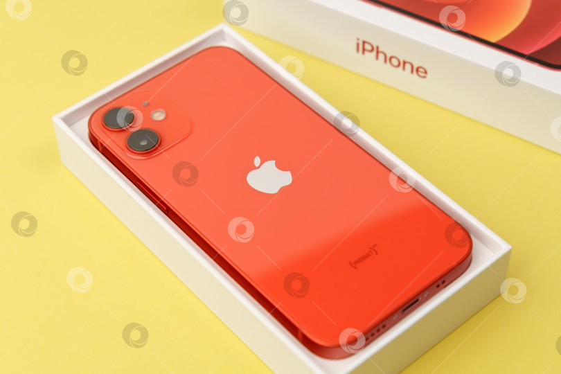 Скачать Тюмень, Россия - 18 июля 2022 года: iPhone 12 mini представлен в красном цвете. Этот мобильный телефон записывает видео в формате 4k в формате Dolby Atmos HDR фотосток Ozero