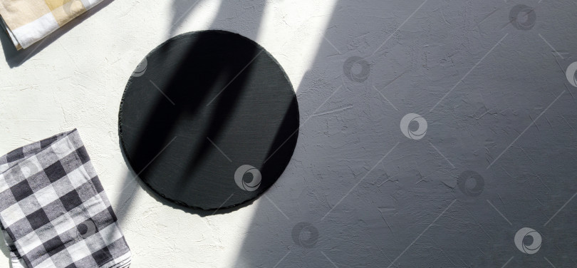 Скачать Круглый камень из черного сланца на фоне белого бетона, вид сверху, место для копирования. фотосток Ozero