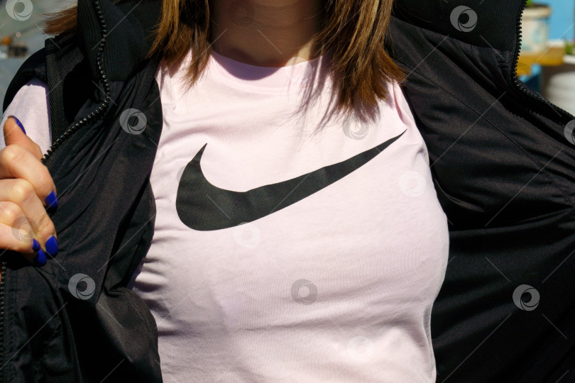 Скачать Тюмень, Россия - 4 июня 2022 года: логотип Nike на женской футболке. Nike - это глобальный производитель спортивной одежды, и магазины running at Nike расположены по всему миру фотосток Ozero