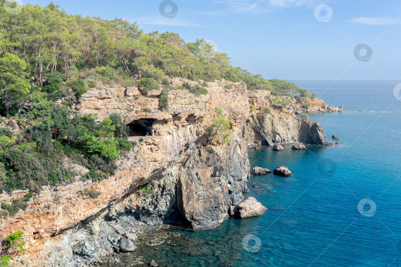 Скачать Средиземноморский морской пейзаж с крутым лесистым побережьем и пещерой фотосток Ozero