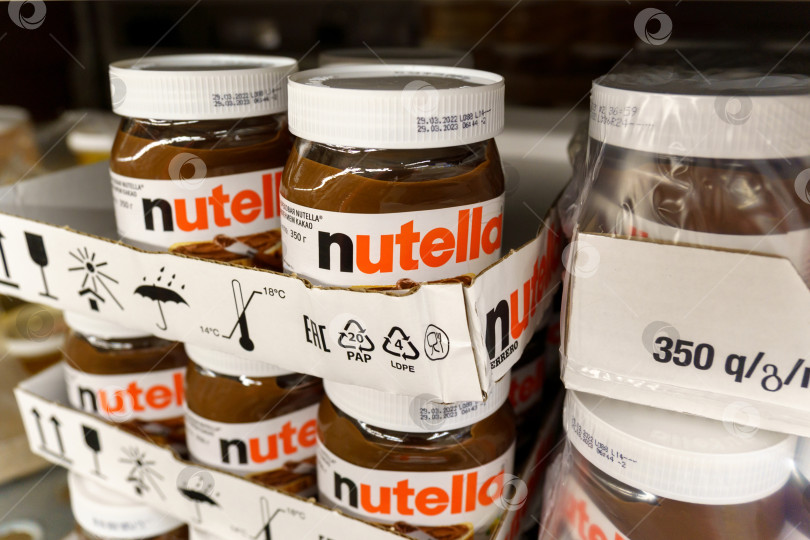 Скачать Тюмень, Россия - 25 мая 2022 года: Nutella, популярная торговая марка подслащенного какао-спреда с фундуком итальянской компании Ferrero. Товары в гипермаркете фотосток Ozero