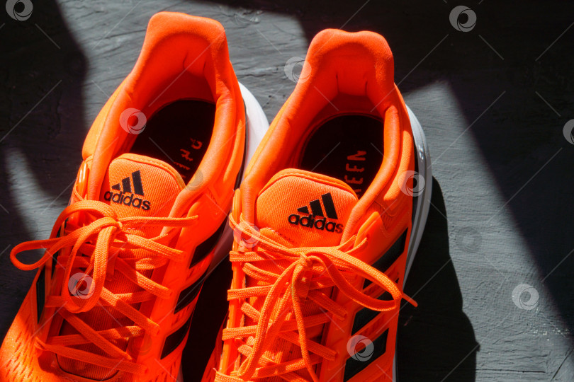 Скачать Тюмень, Россия - 1 июня 2022 года: Кроссовки Adidas оранжево-кораллового цвета, eq21 run. Логотип крупным планом фотосток Ozero