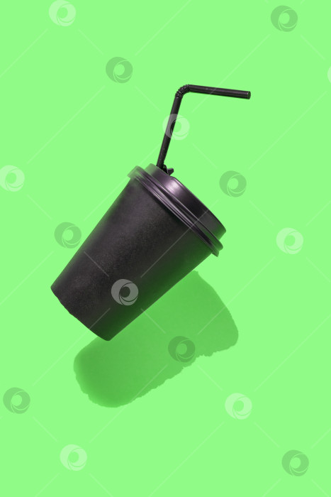 Скачать Бумажный контейнер для кофе с черной крышкой на зеленом фоне. Вертикальная фотография фотосток Ozero