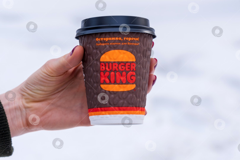 Скачать Тюмень, Россия - 23 февраля 2022 года: логотип компании Burger King на кофейной чашке на размытом зимнем фоне. Избирательный фокус фотосток Ozero