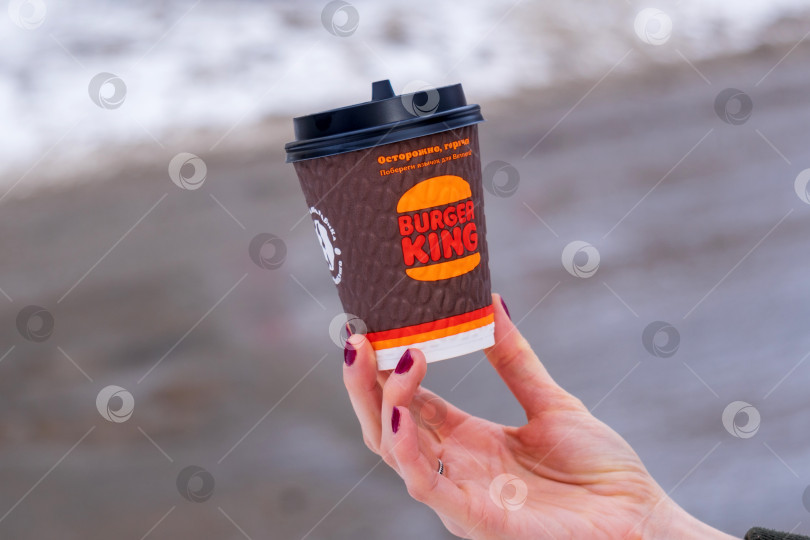 Скачать Тюмень, Россия - 23 февраля 2022 года: логотип компании Burger King на кофейной чашке на размытом зимнем фоне. Избирательный фокус фотосток Ozero