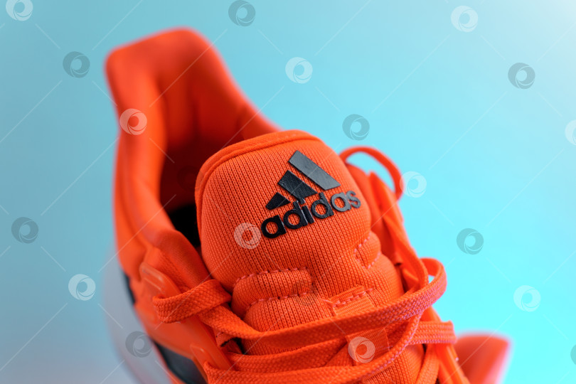 Скачать Тюмень, Россия - 13 ноября 2021 года: Оранжевые кроссовки adidas. Логотип Adidas, многонациональной компании. фотосток Ozero