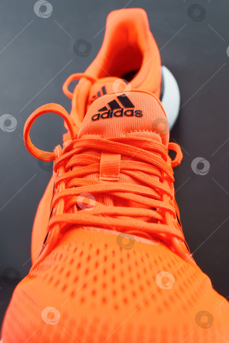 Скачать Тюмень, Россия - 13 ноября 2021 года: Новые кроссовки Adidas оранжевого цвета. Модель изготовлена из переработанных материалов. Вертикальная фотография фотосток Ozero